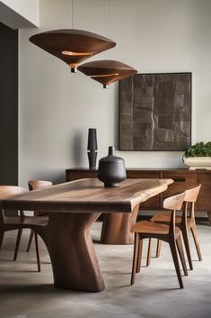 a dining room table and chairs in front of a wall with art work on it