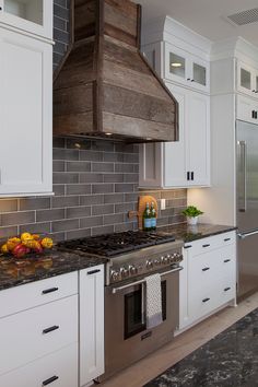 a stove top oven sitting inside of a kitchen next to white cupboards and drawers