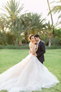 a bride and groom pose for a photo in front of palm trees at their wedding