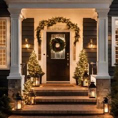 front porch decorated for christmas with wreaths and garlanding on the door, lanterns lit up