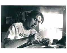 a black and white photo of a man sitting at a table working on some type of paper