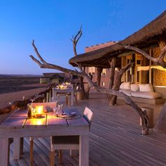 an outdoor dining area with candles lit on the table and chairs in front of it