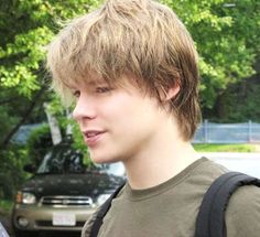 a young man standing in front of a parked car