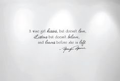 a white wall with three spotlights and a quote written on it that says, a wise girl kisses, but doesn't live