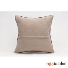 a beige pillow with black piping on the front and side, sitting against a white background