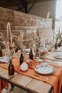 the table is set with plates, glasses and vases for dinner guests to enjoy