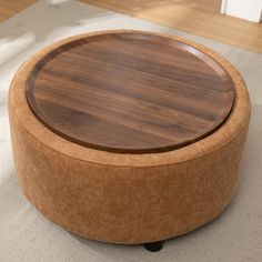 a wooden table sitting on top of a white rug next to a chair and ottoman