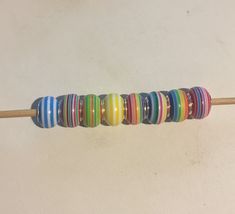 a wooden stick with multi - colored beads on it sitting on the floor next to a wall