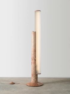 a lamp that is sitting on top of a cement floor in front of a white wall