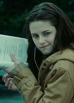 a young woman holding an open book and listening to headphones