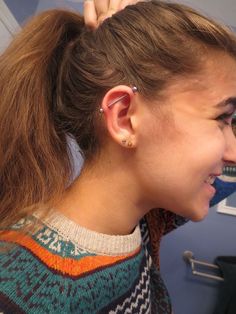 a woman is getting her hair styled by another person in the background with scissors on her head