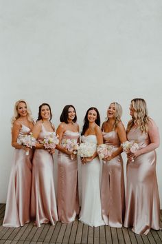 a group of women standing next to each other holding bouquets in their hands and smiling at the camera