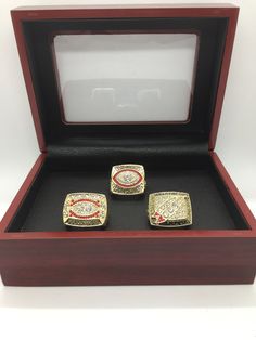 two men's rings sitting in a wooden box on top of a white surface