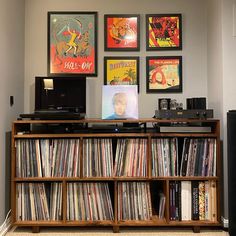 a record player sitting on top of a wooden shelf next to a wall filled with records