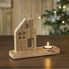 a small wooden house with a lit candle in front of it on top of a table