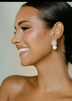 a woman wearing earrings with pearls on the back of her head, smiling and looking off to the side