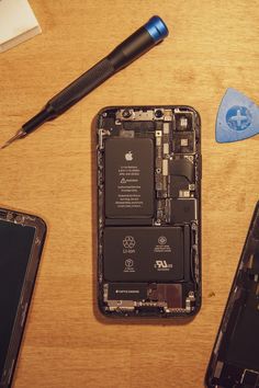 an iphone is shown with its battery removed from the back side and tools next to it