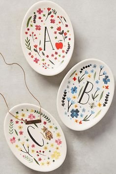 three personalized ceramic dishes with floral designs and the letters a, b, and c