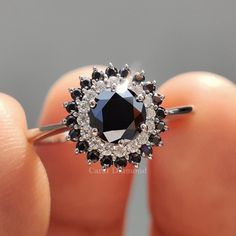 a woman's hand holding a black and white diamond ring