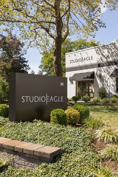 the studio eagle sign is in front of some bushes and trees with a building behind it