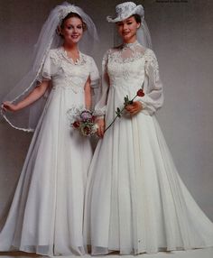 two women in wedding gowns and veils posing for the camera with each other