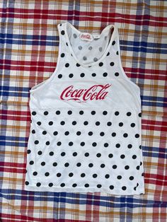 "Very cute vintage Coca-Cola tank top!  Very lightweight and soft 100% cotton, white with black polka dots and red lettering.  There are a few stains, 1 small pin prick on the front plus 1 other towards the side, and 2 towards the bottom on the back, but they are faint and honestly hard to see unless you are looking (see photos).   Tag says size large, though it seems to fit more of a modern woman's small or possibly medium.  Please check measurements to ensure a proper fit: Armpit to armpit (at tips/in line with tops of lower-case letters on graphic): 17\" Length from top of shoulder to bottom of shirt: 24\" Thanks for looking!  Check my shop for more vintage. Items will be shipped in reused packaging." 90s Style Cotton Tank Top For Summer, Retro White Tank Top For Streetwear, White 90s Tank Top For Streetwear, 90s White Tank Top For Streetwear, 90s Style White Tank Top For Streetwear, White Y2k Cotton Tank Top, Cute Polka Dot Sleeveless Top, White Cotton Y2k Tank Top, White Cotton Y2k Style Tank Top