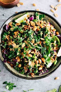 a bowl full of spinach salad with limes and cilantro on the side