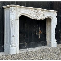 an old white fireplace in front of a black wall