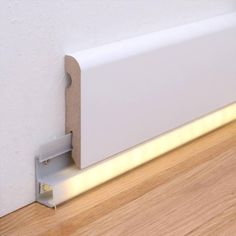 a white wall mounted shelf with a light on it's side next to a wooden floor