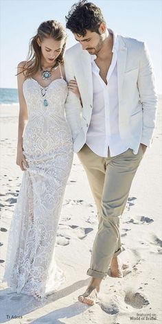 a man and woman are walking on the beach in their wedding attire, with footprints in the sand