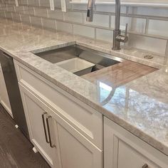 a kitchen with marble counter tops and stainless steel sink faucet in the center