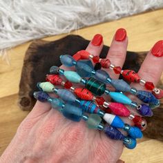 a woman's hand holding several different colored beads