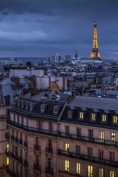 the eiffel tower is lit up at night in paris, france as seen from the roof of an apartment building