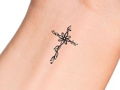 a small tattoo on the wrist of a woman's arm, with flowers and leaves