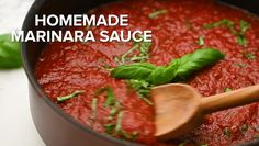 homemade marinara sauce in a pot with a wooden spoon and basil leaves on top