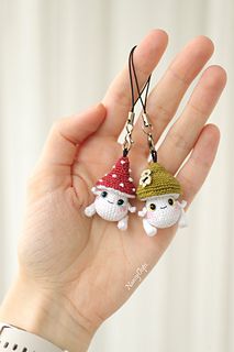 a hand holding two keychains with small animals wearing hats on top of them