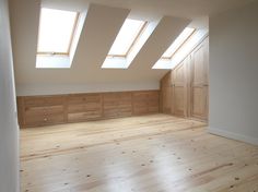 an empty room with wood flooring and skylights in the roof window sill