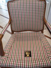 a plaid chair with a wooden arm rest