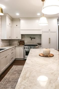 a large kitchen with white cabinets and marble counter tops, along with an island in the middle