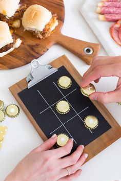 two people are playing a board game on a table with other food and drinks around them