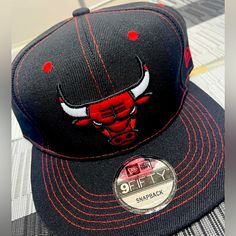 Two Toned Black And Red Bulls Hat With Montage Under Brim. Fitted Red Casual Hat, Casual Black Flat Bill Hat, Casual Fitted Flat Bill Hat, Black Fitted Casual Hat, Casual Red Snapback Hat With Short Brim, Black Flat Bill Snapback Hat For Winter, Fitted Casual Snapback Baseball Cap, Fitted Casual Snapback Hat For Sports, Fitted Casual Snapback Hat