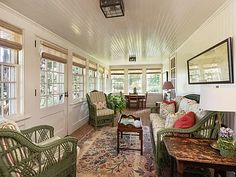 a living room with wicker furniture and lots of windows on the wall above it