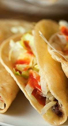 three tortillas on a white plate with condiments