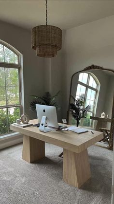 a laptop computer sitting on top of a wooden desk in front of a large mirror