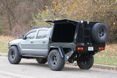 the truck is parked on the side of the road in front of some trees and bushes