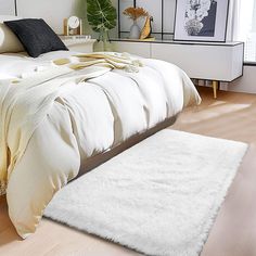 a white bed sitting in a bedroom on top of a hard wood floor next to a window