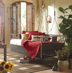 a living room filled with furniture and lots of windows covered in sun shining through shutters