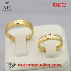 two gold wedding rings with princess cut diamonds on each band, set in a white ring holder