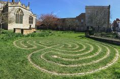 a large circular maze in the middle of a grassy area next to a building and trees