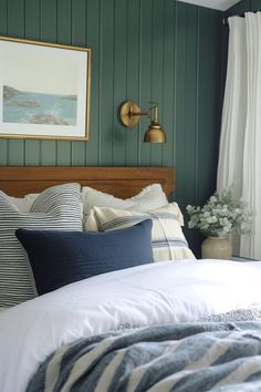 a bedroom with green painted walls and white bedding, blue striped throw pillows on the bed